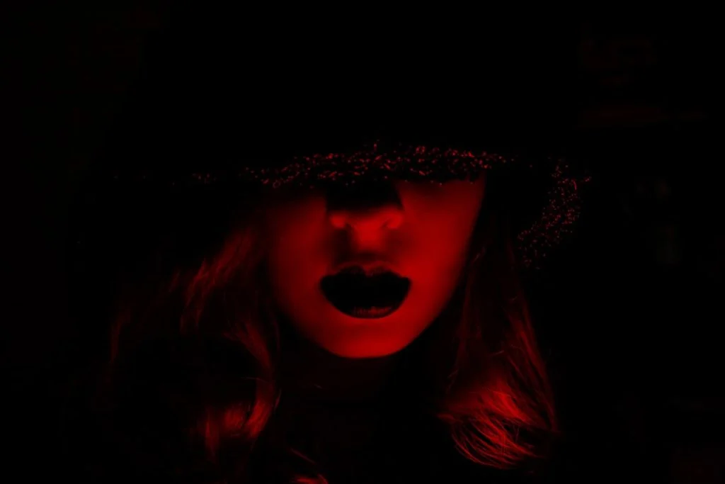 A figure bathed in deep red light with a dramatic hat, evoking the gothic vampire rock atmosphere of The Vampire Lestat on AMC